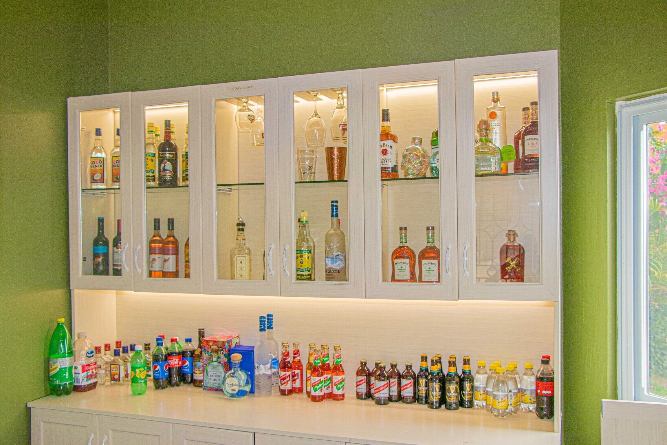 Eine Bar mit mehreren Spirituosenflaschen und Gläsern auf Regalen und Theken.