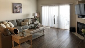 Un salon spacieux avec un canapé gris, une table basse en bois et un téléviseur.