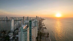 Un paisaje urbano costero con rascacielos y una playa al atardecer.