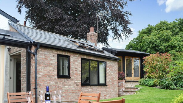 A brick house with a garden, a patio table with chairs, and a bottle of wine. - 2 bedroom accommodation in Tibthorpe, near Driffield (Tibthorpe, near Driffield)