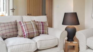 A white sofa with plaid cushions, a wooden door, and a lamp on a small wooden table. - 2 bedroom accommodation in Tibthorpe, near Driffield (Tibthorpe, near Driffield)