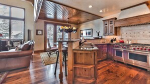 Tilava keittiö, jossa on puiset kaapit, sisäänrakennettu uuni ja suuri keittiösaareke, jossa on pesuallas.