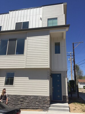 Un edificio de dos pisos con base de piedra, una puerta azul y un número de calle visible.