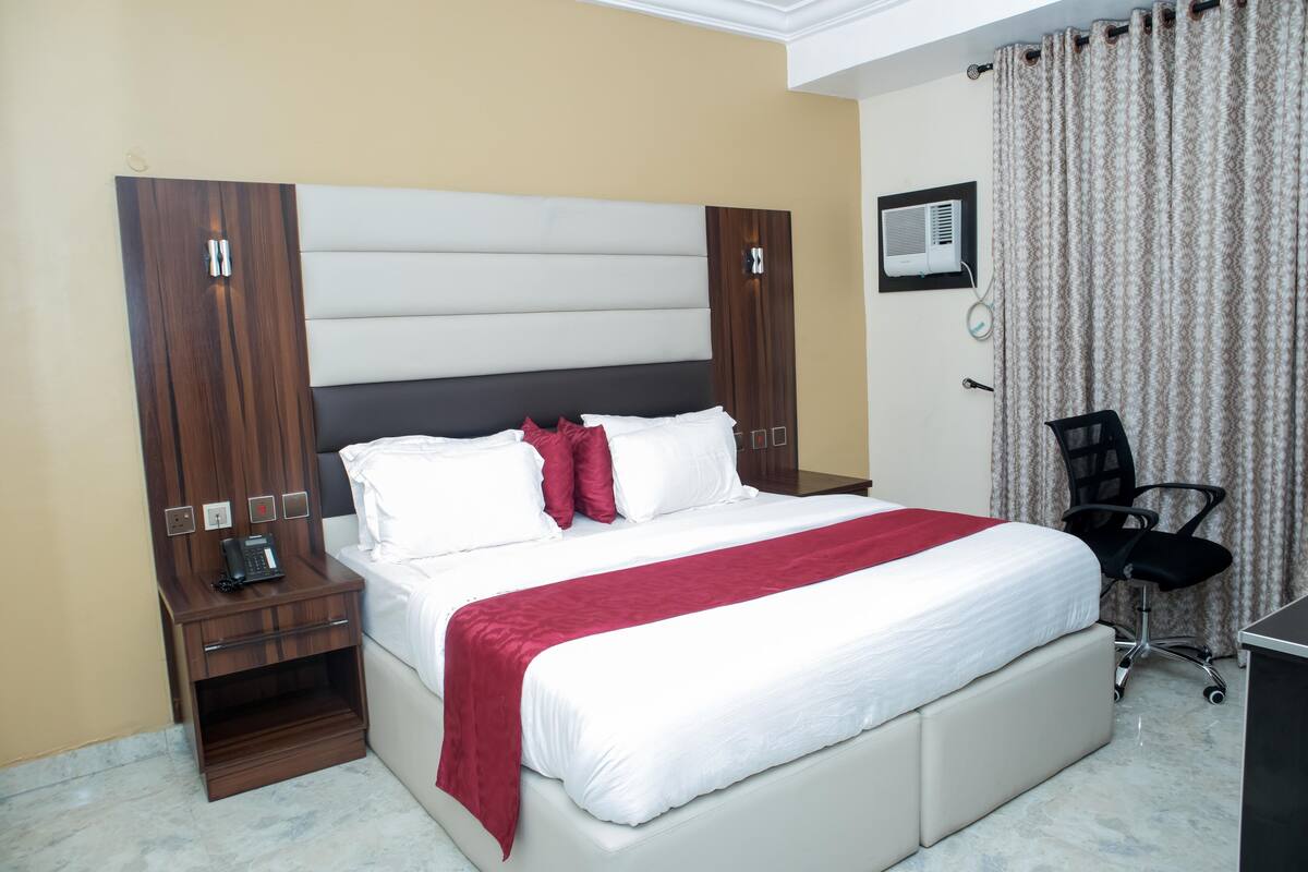 Une chambre d’hôtel avec un grand lit, une table de chevet avec un téléphone, un bureau et une chaise.