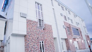 Ein modernes Gebäude mit einer Fassade aus weißem und rotem Backstein, großen Fenstern und einem gepflasterten Eingangsbereich.