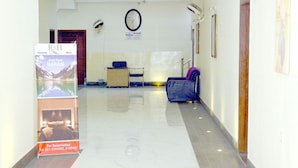 Un passadís d'hotel amb una recepció, un rellotge i un cartell a la paret.