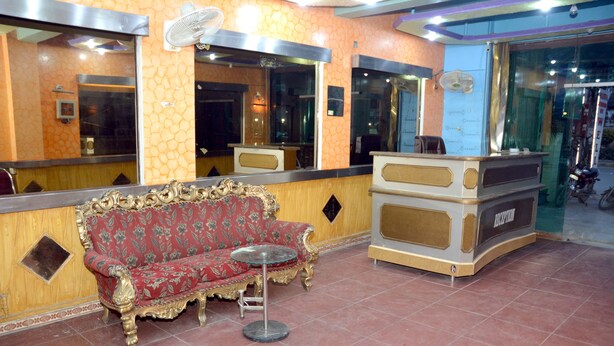 A reception area with a red floral sofa, a small round table, and a reception desk.