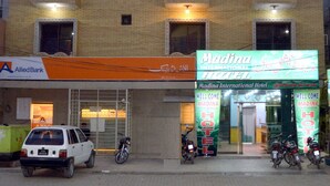 A multi-story building with a sign for 'Madina International Hotel' and a visible storefront for 'Allied Bank'.