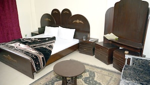 A hotel room with a large bed, a bedside table, a nightstand, a mirror, and a small round table.