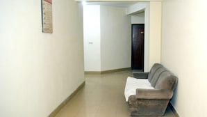A hallway with a couch, a poster on the wall, and a door at the end.