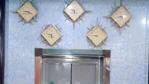 An elevator with a green door, surrounded by blue patterned walls and wooden paneling.