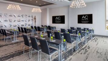 A conference room with multiple tables and chairs, AC Hotels Marriott branding, and a patterned carpet.