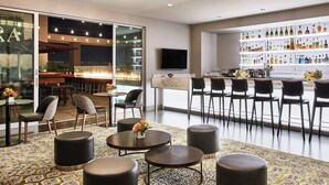 A modern bar area with a bar counter, seating, and a variety of bottles and glasses.