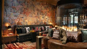 Una sala de estar acogedora con chimenea, un sofá de cuero negro y una alfombra estampada.
