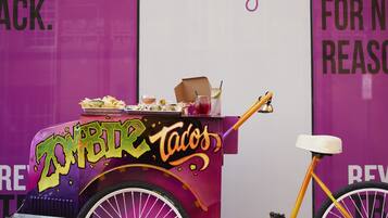 A purple taco cart with a bicycle parked beside it.