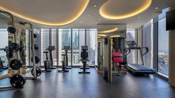 Ein modernes Fitnessstudio mit verschiedenen Trainingsgeräten, großen Fenstern und Blick auf die Stadt.