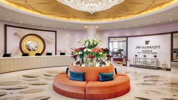 A luxurious lobby with a central seating area, a chandelier, and a JW Marriott sign.