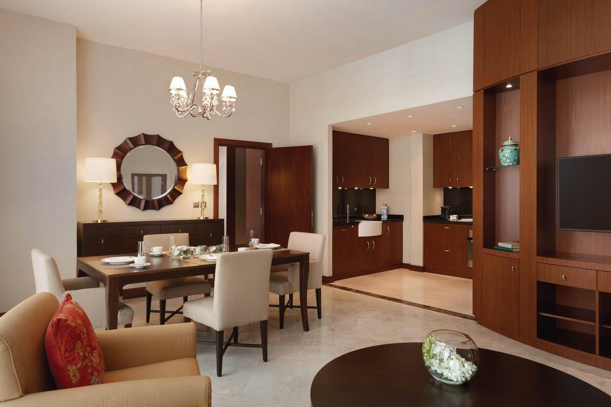 A modern living room with a dining area, a kitchen, and a TV.