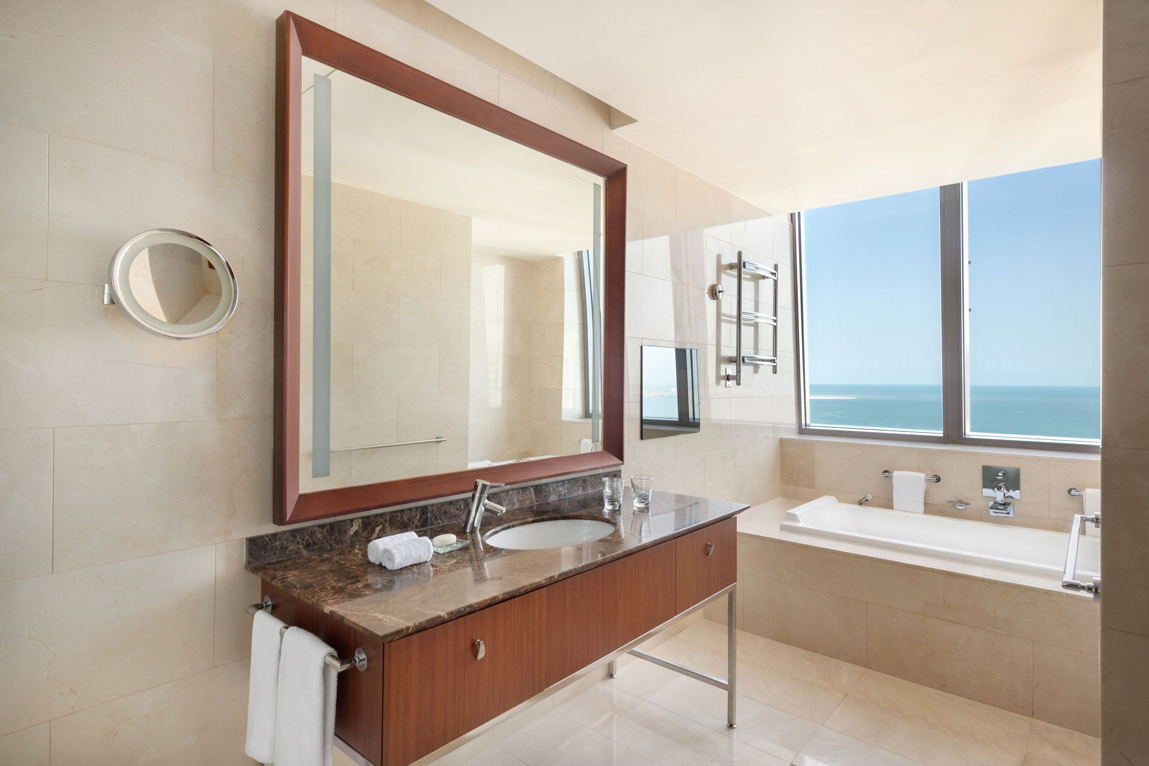 Un baño moderno con un espejo grande, un lavamanos y una bañera.