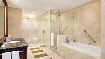 A modern bathroom with a glass-enclosed shower, a marble sink, and a large bathtub.