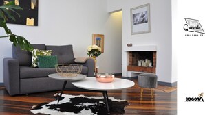 Een moderne woonkamer met een grijze bank, een ronde salontafel en een open haard.