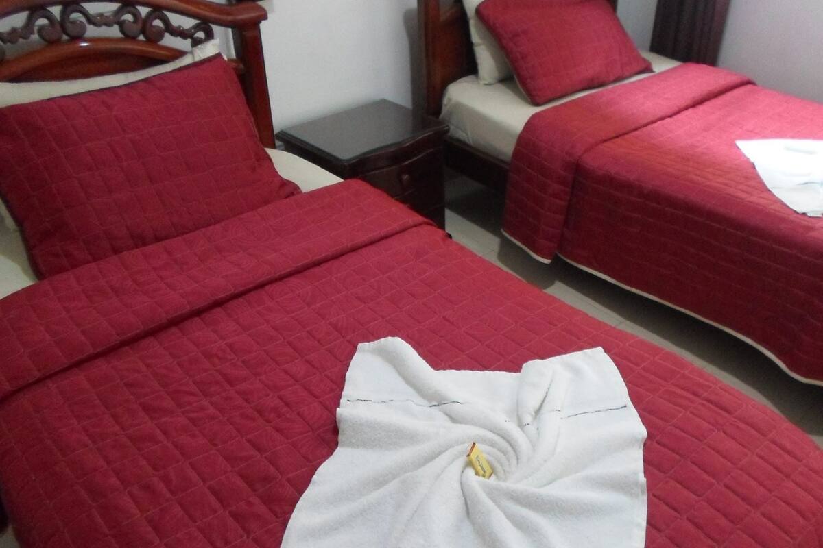 A hotel room with two beds, each with red bedding and white towels.