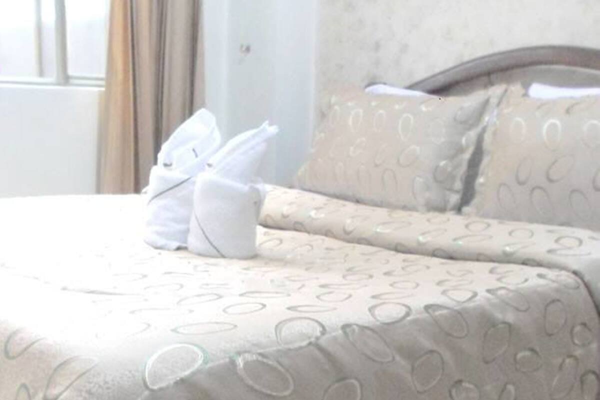 A neatly made bed with a patterned bedspread and two pillows.