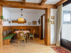 A cozy dining area with wooden furniture, a table with a checkered tablecloth, and a hanging lamp.