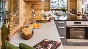 A modern kitchen with wooden cabinetry, a built-in stove, and a dining area with a view of the outdoors.