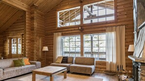 A log cabin interior with a sofa set, a coffee table, and a fireplace.