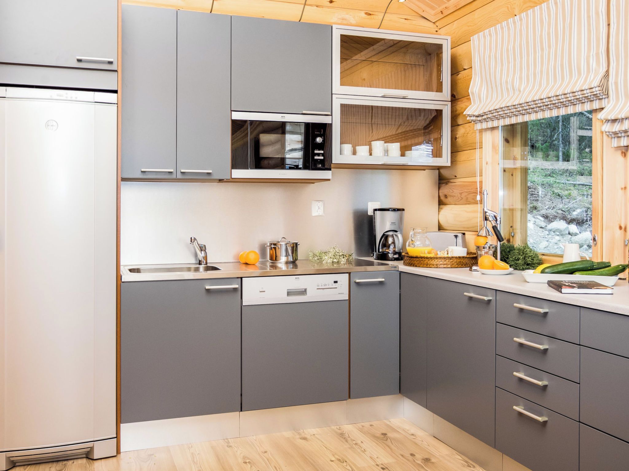A modern kitchen with grey cabinets, a built-in microwave, and a coffee machine.