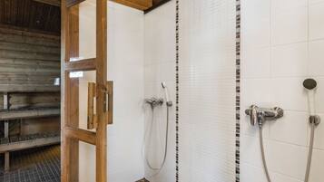 A shower area with a wooden door, white tiled walls, and a tiled floor.