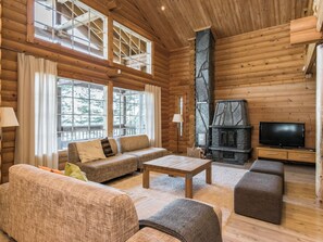 A log cabin interior with a sofa set, a coffee table, a fireplace, and a television.