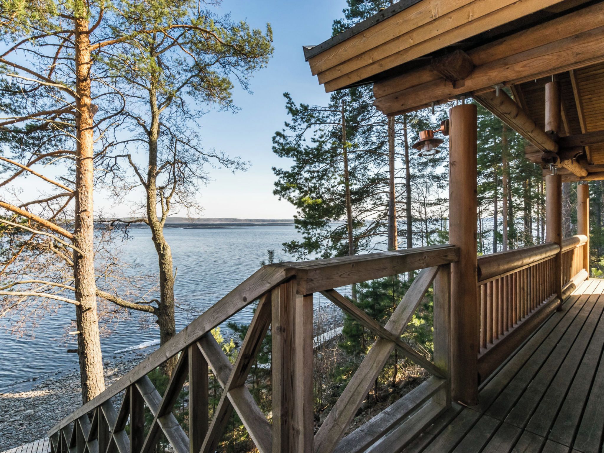 A wooden deck with a railing overlooking a body of water and trees.