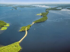 An aerial view of a coastal area with a long, narrow landform extending into the water, surrounded by dense green vegetation. - Roopenranta by Interhome (Asikkala)