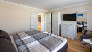 Une chambre à coucher comprenant un lit, une armoire, une télévision et un espace bureau.