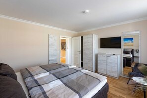 Ein Schlafzimmer mit Bett, Kleiderschrank, Fernseher und Schreibtisch.