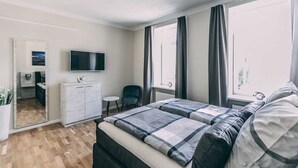 Un dormitorio con cama, televisor, escritorio y silla.