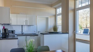 Una cocina moderna con armarios blancos, una mesa de comedor de madera y vistas a través de un gran ventanal.