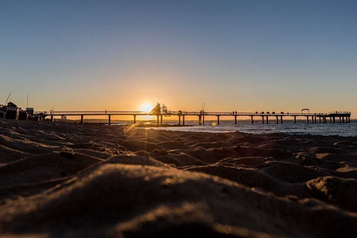 Um cais se estendendo sobre águas calmas ao pôr do sol.