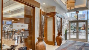 A hotel lobby with a reception desk, a sign reading "delights", and a view of the city through large windows. - TOP 38th  FLOOR 1 BR PENTHOUSE! BALCONY! SPHERE, F1 Views, POOL-NO RESORT FEES! (Las Vegas)