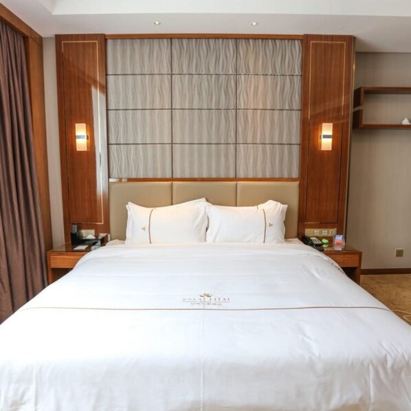 Habitación de hotel con una cama grande, cabecero de madera y dos mesitas de noche con lámparas.