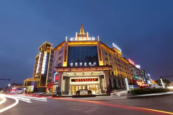A hotel with a prominent entrance, large windows, and illuminated signage.