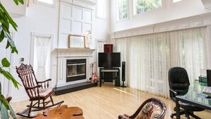 Amplia sala de estar con chimenea, televisor y piano.