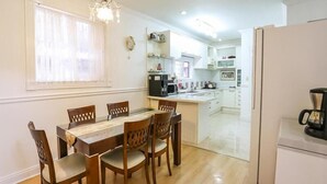 Una cocina moderna con armarios blancos, una mesa de comedor con sillas de madera y una cafetera en la encimera.