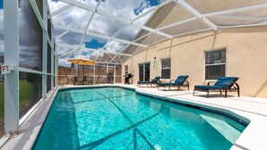 Ein Swimmingpool mit Liegestühlen und einer überdachten Terrasse.