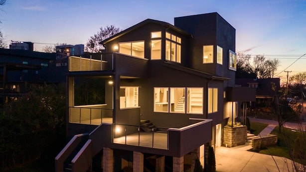 Ein modernes mehrstöckiges Haus mit Balkon und einer Treppe, die zu den oberen Stockwerken führt.