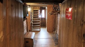 A wooden interior with a staircase leading to an upper level, a bench, and a metal rack. - Feu de Joie by Interhome (Segnas)