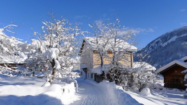 A snow-covered village with traditional wooden houses, a clear sky, and a mountain in the background. - Feu de Joie by Interhome (Segnas)