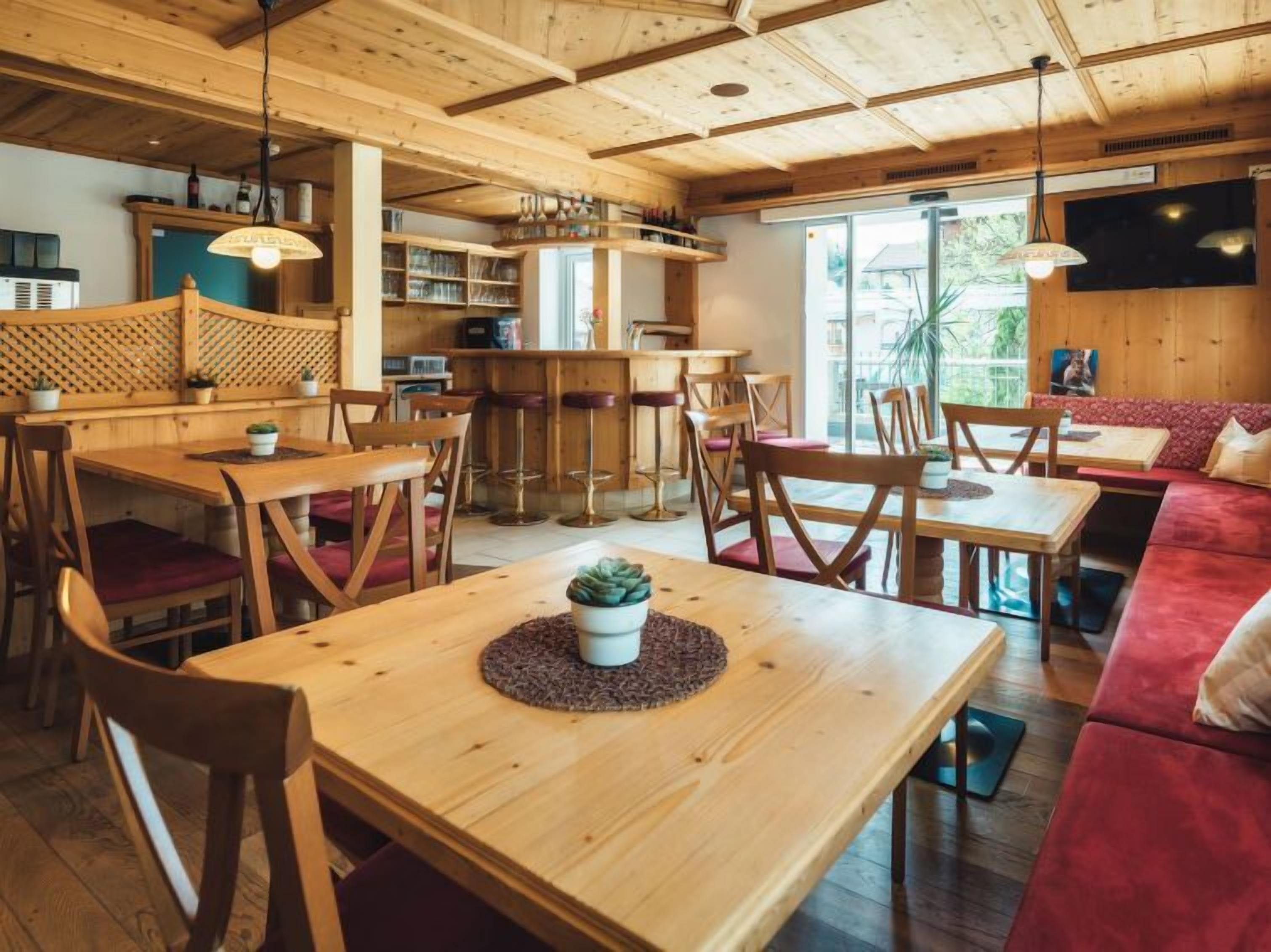 Un restaurant chaleureux, décoré de bois, avec plusieurs espaces où s’asseoir, notamment des tables et un canapé.